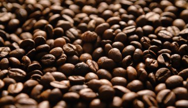 Yakın plan kahve çekirdekleri. Koyu kahve tanecikli geniş bir arka plan.