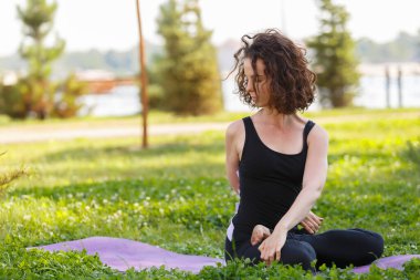 Sabahları yoga minderinde kıvırcık saçlı güzel bir kadın. 20 'li yaşlarda açık havada esneme hareketleri yapan tatlı bir Ukraynalı kız.