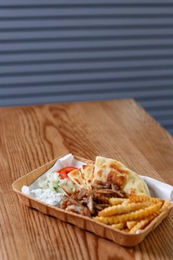 Yunan souvlaki 'si fast food restoranında patates kızartması ve beyaz yoğurt ile servis edilir. Yunanistan 'dan geleneksel sokak yemekleri geri dönüştürülebilir kağıt tabakta servis ediliyor