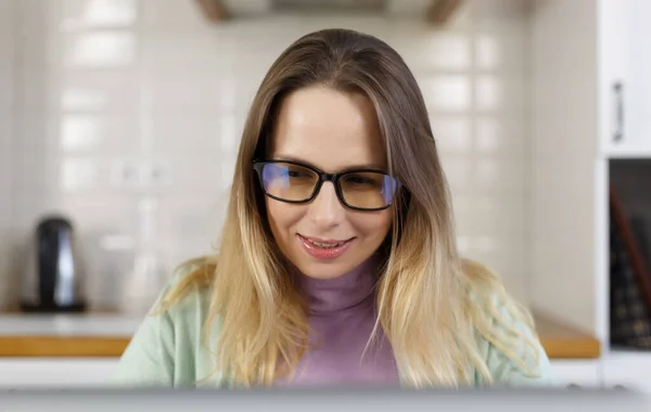 戴眼镜 从电脑屏幕上读文字的快乐白人妇女的画像 在家里用笔记本电脑工作的快乐的成年女性 — 图库照片