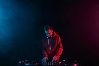 Kulüp DJ 'i gece kulübündeki bir partide plak plaklarıyla ses mikserini karıştırıyor. Genç yetişkin bir erkek disk jokeyi rolünde oynuyor.