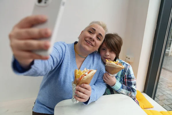 在希腊餐馆吃饭时 妈妈带着智能手机自拍 快乐的家庭在周末享用快餐午餐 — 图库照片