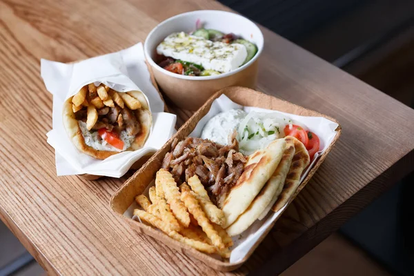 希腊快餐是用来带走的 传统的皮塔苏夫拉基 希腊沙拉和皮塔与薯条在可循环利用的纸盘餐具在桌上 没有人 — 图库照片