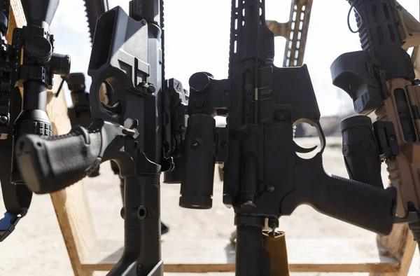 stock image Modern American assault rifles equipped with optical scopes and magnifiers on weapon stand at outdoor shooting range