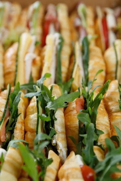 Büyük bir kutu taze kruvasan, roka, sebze ve kırmızı balık bir yerde yemek servisi için servis ediliyor.