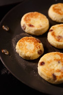 Lezzetli Ukrayna şurubu mutfakta pişiriliyor. Sıcak tavada kızaran peynirli kekler. Ukrayna 'dan geleneksel tatlı yemekleri.