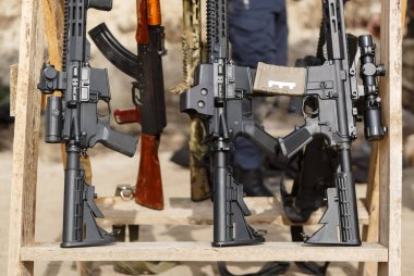 Modern Amerikan saldırı tüfeği büyüteçlerle donatılmış ve hassas atış için optik dürbünler. Antrenman sahasındaki silah standında duran bir çift tüfek.