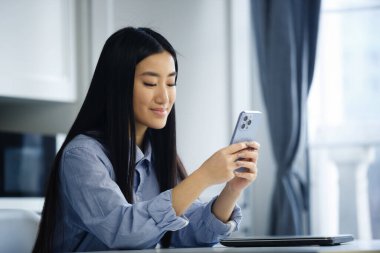 Mutlu Asyalı kız cep telefonu uygulamasında SMS mesajı yazıyor. Neşeli Vietnamlı kadın akıllı telefonla iletişim kuruyor.