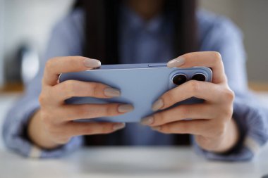 Oyuncu akıllı telefondan mobil oyunlar oynuyor. Genç kız modern bir aletle online video oyunu oynuyor.