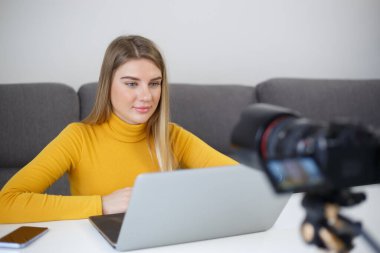 Video blogcusu eğitim kurslarını filme alıyor. Genç sarışın kadın blog için kamerada konuşuyor.