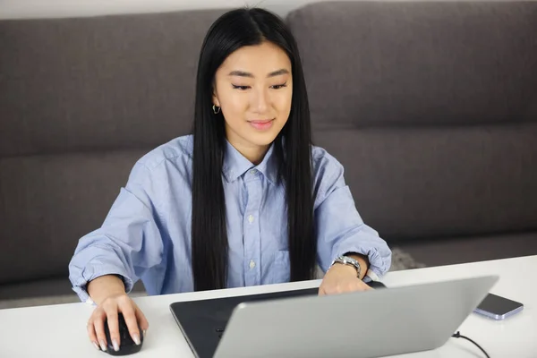 自宅のノートパソコンで働いている幸せなアジアの女の子 陽気なベトナム人女性はノートパソコンで遠くの仕事をしている — ストック写真