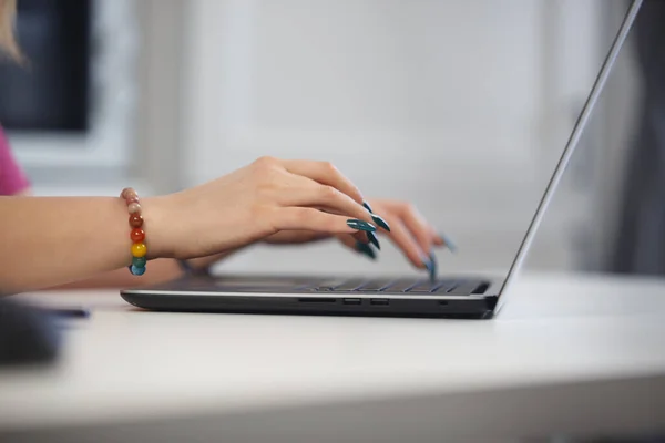 ノートパソコンのキーボードに長い爪の入力テキストを持つ女性 — ストック写真