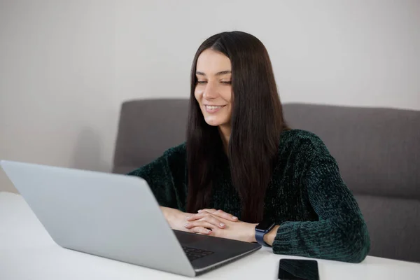 Happy brunette woman working on laptop at home. Cheerful white female person doing work on notebook computer