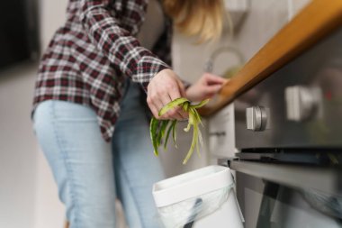 Kadın eli geri dönüşüm için gübre kabuğuna sebze kabuğu atıyor. Evde sağlıklı yemekler pişiren ve mayalı bir bokashi kutusunda organik atık gübreleyen bir kadın.