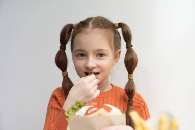 Güzel beyaz çocuk patates kızartması yiyor. At kuyruklu şirin Ukraynalı çocuğun portresi bir kafede fast food yiyor.