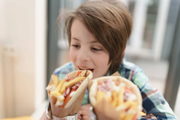 かわいい男の子ジャイロサンドイッチかむ 小さな子供がカフェで伝統的なギリシャのファーストフードを食べています — ストック写真