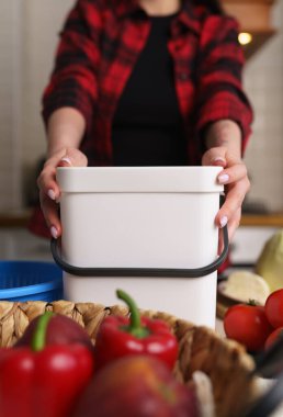 Housewife using compost bin in a domestic kitchen. Female person holds plastic container with bokashi ferment for organic waste. Sustainable lifestyle concept clipart