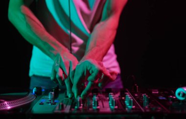 Sahnede müzik çalan kulüp DJ 'i. Profesyonel disk şakasının, plak plaklarından müzik parçalarını ses karıştırıcı ile karıştırırken çekilmiş bir fotoğrafını kapat