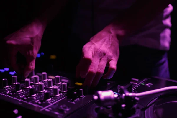 Hip hop DJ mixing music in dark night club. Hands of disc jockey playing set on stage
