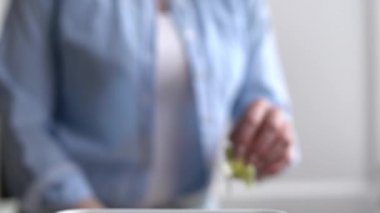 Bir kadın gübre kutusunda yemek artıklarını geri dönüştürüyor. Kadın evde yemek pişiriyor ve gübrelenebilir organik atıkları bir Bokashi konteynerine atıyor.