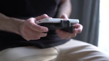 Mobil oyun oynayan bir erkek modern bir akıllı telefonda eklenmiş joystick ile