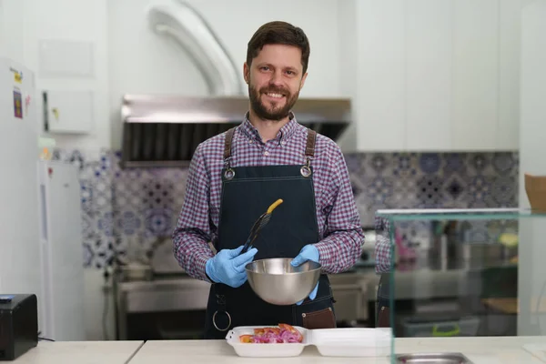 Cheerful white man working in a Greek fast food restaurant. Good looking adult male person with beard posing with a smile in a commercial kitchen