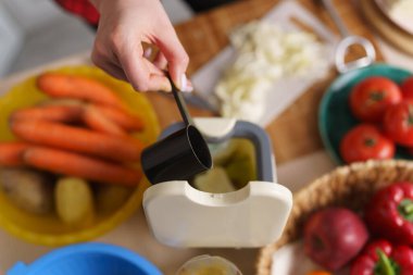 Kadın gübre kutusuna bokashi mayası döküyor. Kadın evde sağlıklı yemekler pişiriyor ve yemek artıklarını bir konteynırda geri dönüştürüyor.