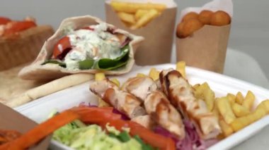Yunan kalamaki, souvlaki ve jiroskopları bir restoranda öğle yemeği için hazırlandı. Geleneksel Akdeniz fast food 'u bir lokantada yemek için hazırlandı ve 4K' da dönen bir masada çekildi.