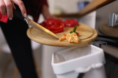 Kadın aşçı organik yiyecekleri gübre kutusunda geri dönüştürüyor. Kadın, evcil bir Bokashi konteynırına gübre atıyor.