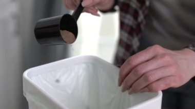 Kadın gübre kutusuna bokashi mayalama kepeği döküyor. Sorumlu kadın evde organik gıda atıklarını geri dönüştürüyor.