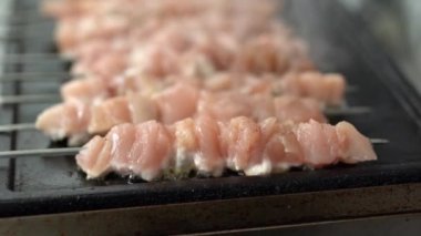 Restoran mutfağında sıcak tavada kızartılan şişler üzerindeki taze kırmızı et filetosu. Ticari bir mutfakta ızgarada pişirilen metal şişler üzerinde domuz eti.