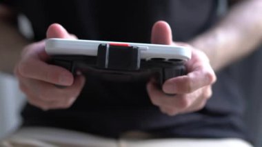 Oyuncu akıllı bir telefonla online video oyunu oynuyor. Mobil oyunlar oynamak için oyun yastığı olan modern bir aygıt kullanan oyuncu