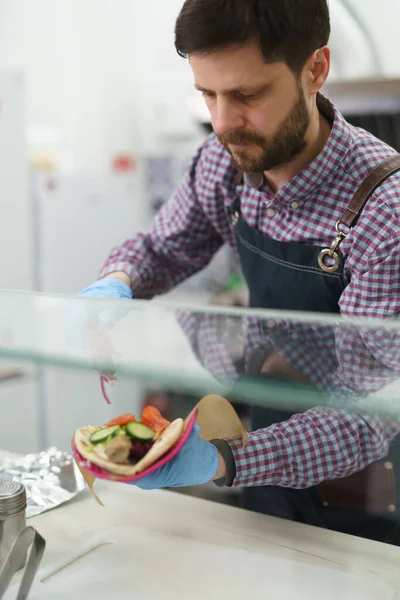 厨师在一家希腊快餐店里吃陀螺三明治 准备带走 在餐馆里准备午餐的有重点男性 — 图库照片