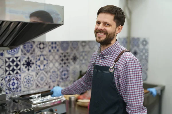 一个快乐的厨师在商业厨房工作的画像 有胡子 面带微笑的友善男性在餐馆里摆姿势 — 图库照片
