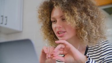 İnternet konferansında konuşan kıvırcık saçlı, arkadaş canlısı beyaz bir kadın. Neşeli beyaz kadın web kamerasında konuşuyor.