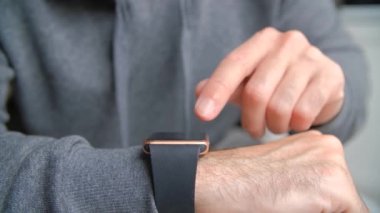 Akıllı saat kullanan bir erkek. Genç bir adamın akıllı bir bilek saat ekranına hafifçe vurduğu videoyu kapat.