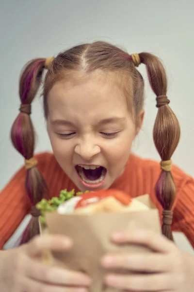 空腹の少女はサンドイッチをかむ ギリシャのレストランでピタ スヴラキの軽食を飲んで面白い白い子供の肖像画 — ストック写真
