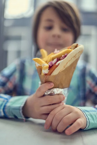 かわいい男の子はファーストフードレストランでギリシャのジャイロサンドイッチを食べています お昼にピタ ソブラキを楽しむ小学生 — ストック写真