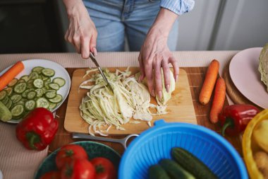 Salata için lahana doğrayan kadın. Kadın evde sağlıklı vejetaryen yemeği hazırlıyor.