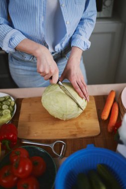 Ahşap bir tahtada bıçakla lahana kesen bir kadın. Sebzeli sağlıklı vejetaryen salatası hazırlayan kadın.