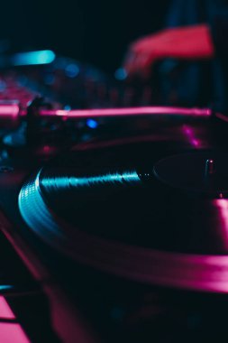 Turntable, karanlık bir gece kulübündeki bir partide vinil plak çalıyor. Tekno DJ sahnede plakları karıştırıyor