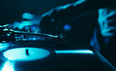 Dj turntable karanlık gece kulübünde müzik eşliğinde vinil plak çalıyor. Disk jokeyi bir tekno festivalinde gösteri yapıyor. 