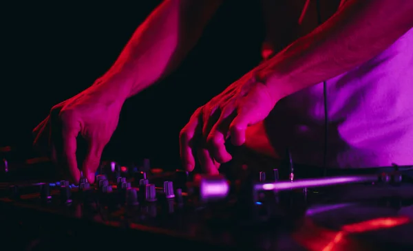 stock image Hands of a disc jockey mixing music with a sound mixer device. Disc jockey playing techno set in a dark night club