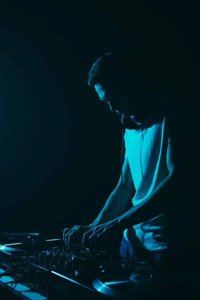 青いステージライトでテクノミュージックを演奏するDjのシルエット クラブディスクジョッキーは暗闇の中でステージ上で実行 — ストック写真