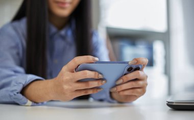 Akıllı telefondan online oyun oynayan genç bir kız. Tanımlanamayan kadın, modern bir aletle video oyunları oynuyor.