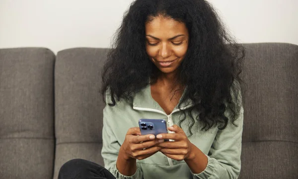 Mujer Negra Alegre Sentada Sofá Casa Escribiendo Mensaje Sms Teléfono — Foto de Stock