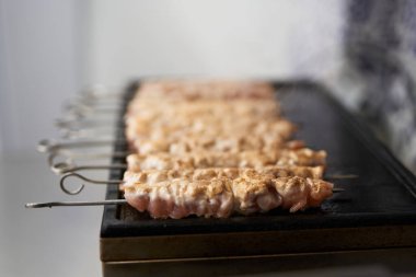 Ticari bir mutfakta elektrikli ızgarada pişirilen şişte domuz eti filetosu. Geleneksel Akdeniz yemekleri öğle yemeği için kızartılıyor