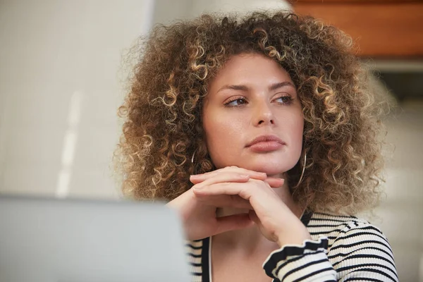 漂亮的白人女人卷曲着卷发 在电脑前思考解决问题的办法 自由撰稿人的肖像 — 图库照片