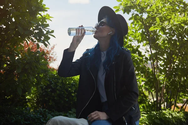 Mångsidig Kvinna Med Blått Hår Dricker Vatten Från Återanvändbar Glasflaska — Stockfoto
