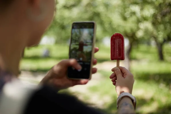 小女孩手里拿着一张冰淇淋的照片 一个无法辨认的女人用智能手机相机拍了一张甜点的照片 — 图库照片